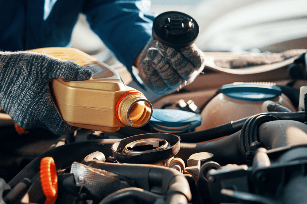 Back to School Car maintenance in Newport, NH by Promex Auto. Mechanic pouring fresh motor oil during an oil change service as part of regular car maintenance at an auto repair shop.