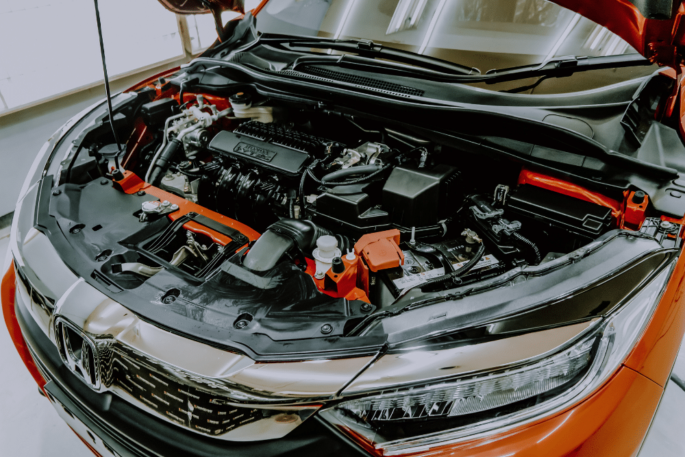 Japanese Auto Repair in Newport, NH by Promex Auto. The engine appears to be housed in a Honda model, and there are noticeable components such as the engine, wiring, and various parts under the hood.