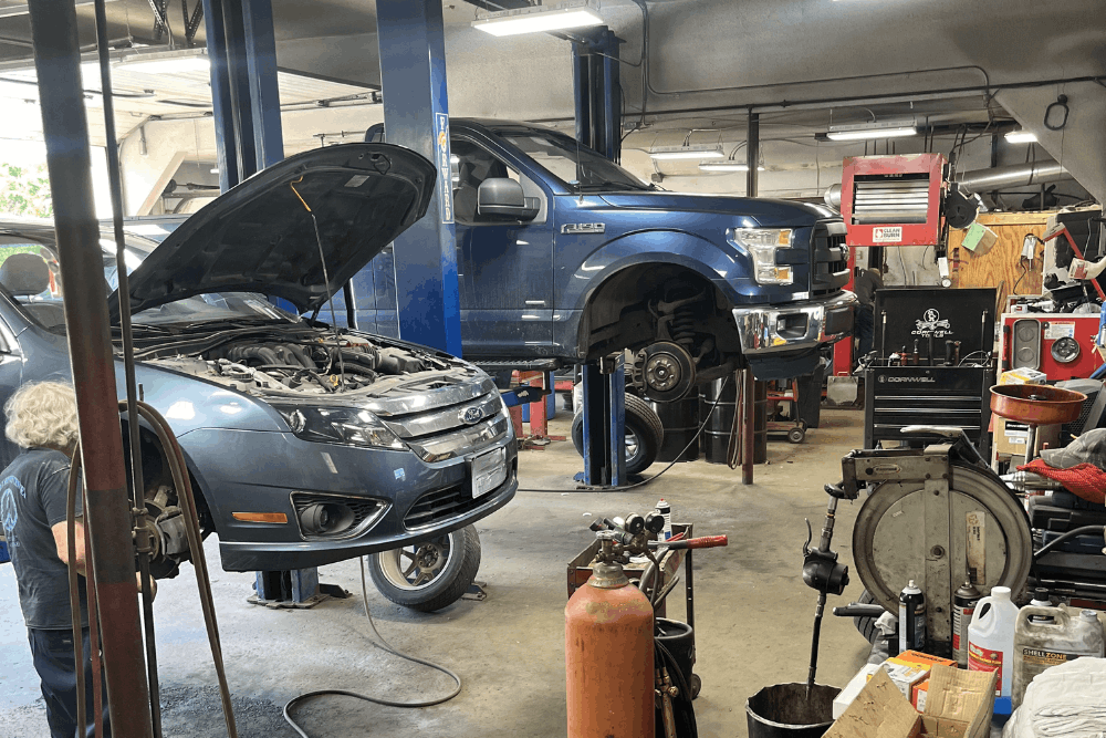 Auto repair near Newbury, NH, at Promex Auto and Tire. Auto repair shop with multiple vehicles on hydraulic lifts undergoing professional maintenance, brake repair, suspension service, and general automotive repairs by experienced technicians.